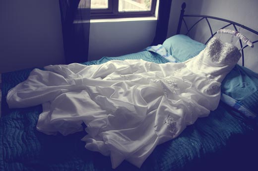 white wedding dress spread out on a bed
